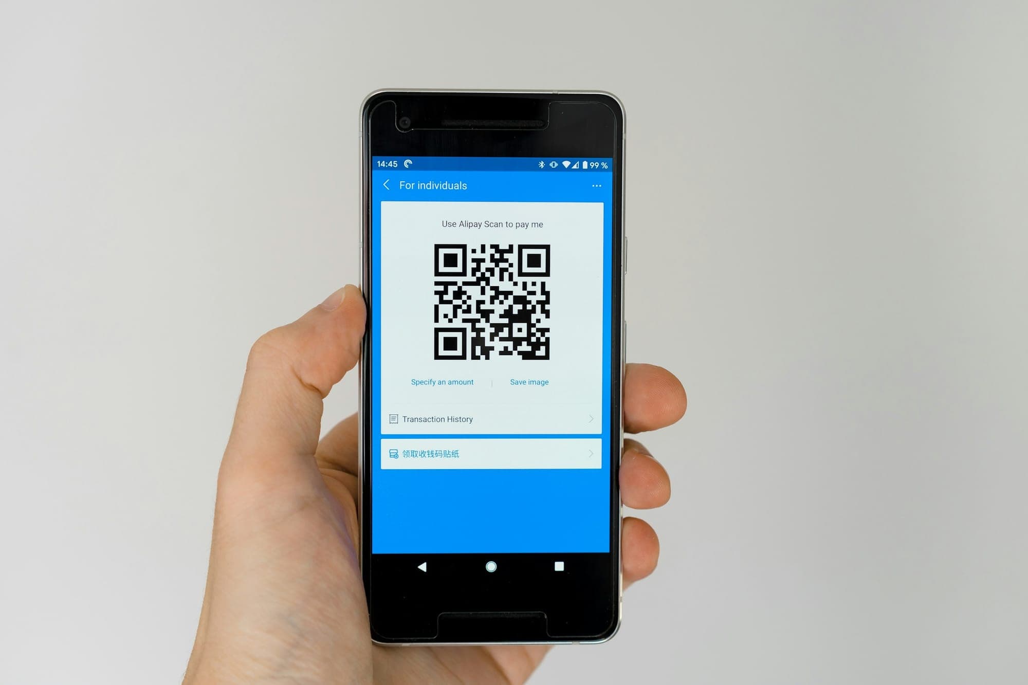 Eine Hand hält ein Smartphone mit einem Alipay-Zahlungs-QR-Code
