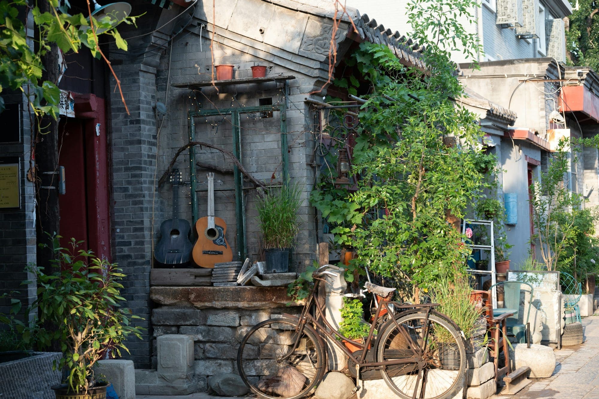 Ein Fahrrad und Topfpflanzen vor einem Hofhaus in einem Hutong im Pekinger Bezirk Dongcheng