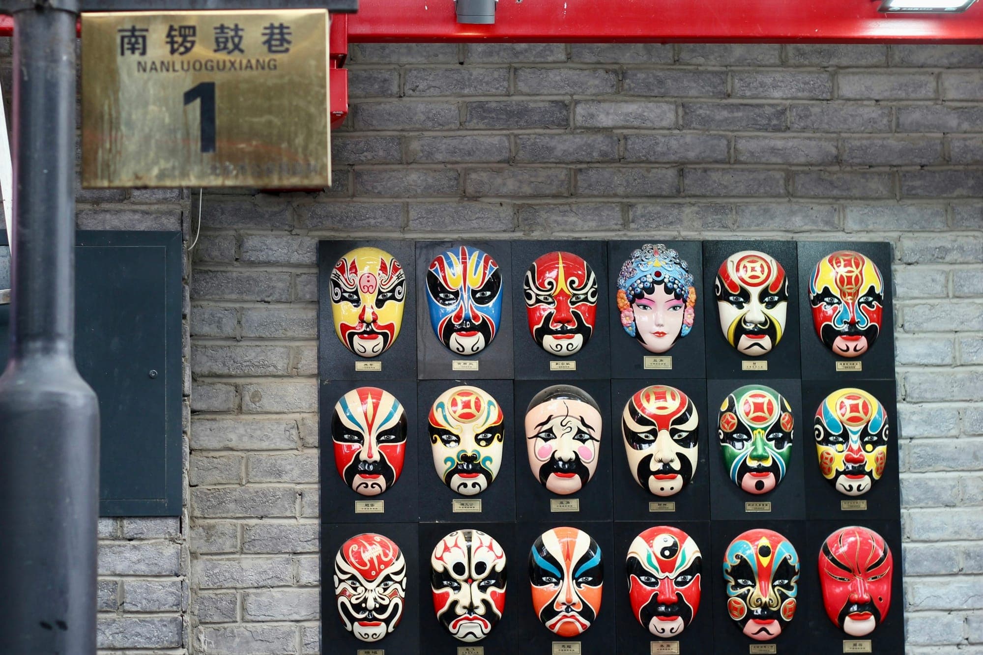 Bemalte Masken der Peking-Oper an einer Wand in Nanluoguxiang, Peking