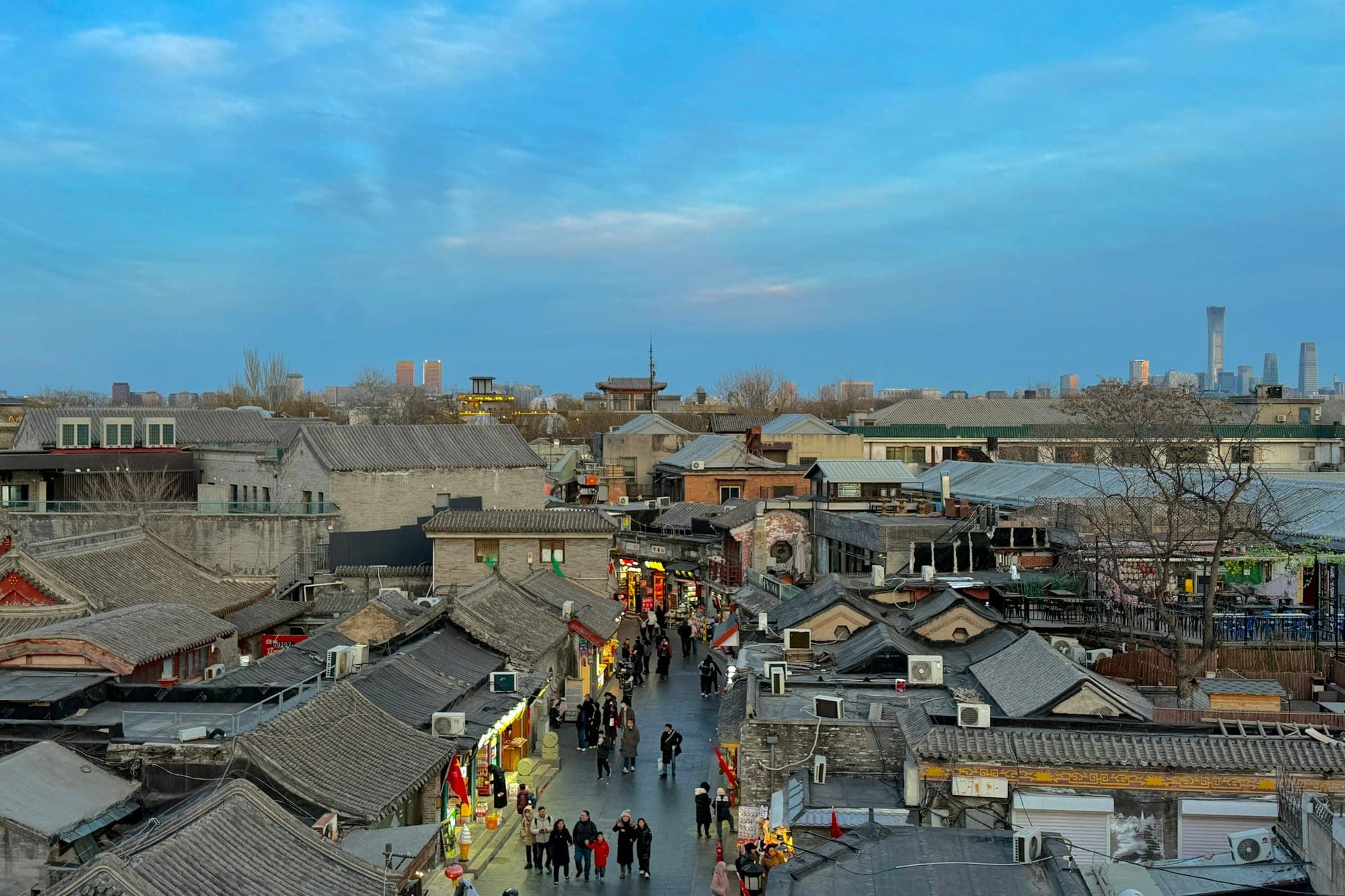 Grau gedeckte Dächer und eine belebte Gasse in der Altstadt von Peking