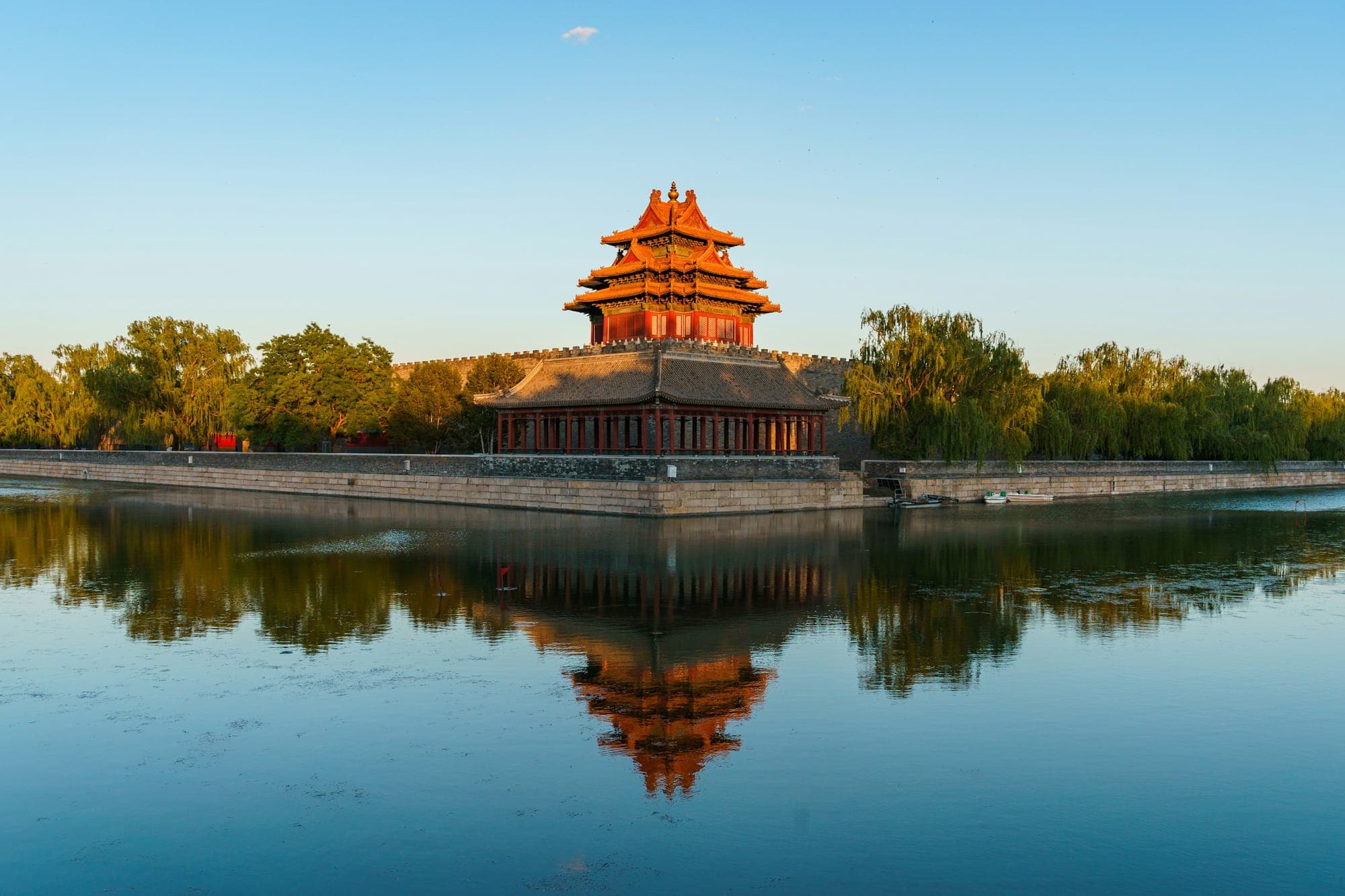 Une tour d'angle de la Cité interdite reflétée dans les douves au lever du soleil, Pékin
