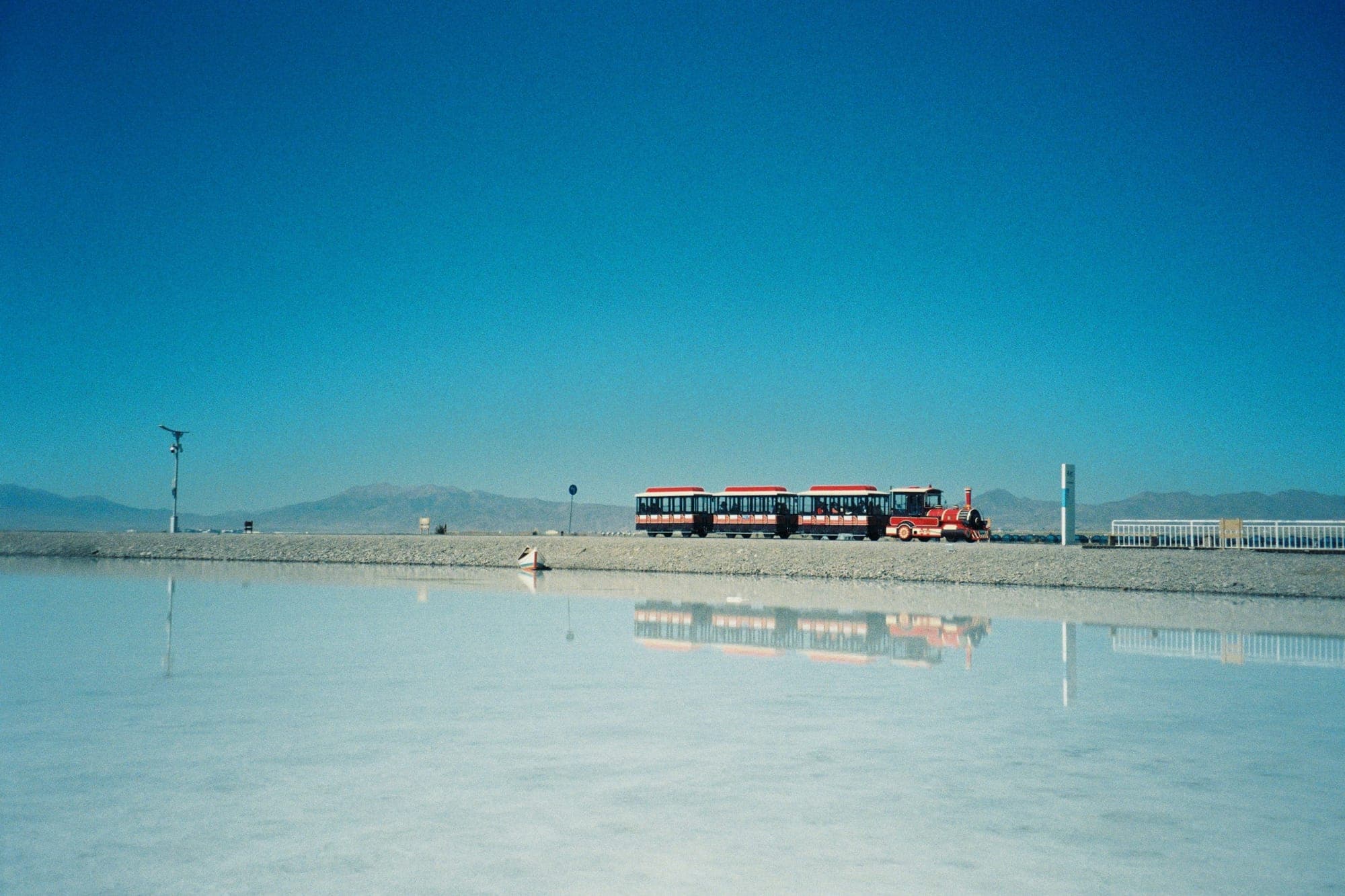 Un tren turístico reflejado en la superficie del lago salado de Chaka, Qinghai