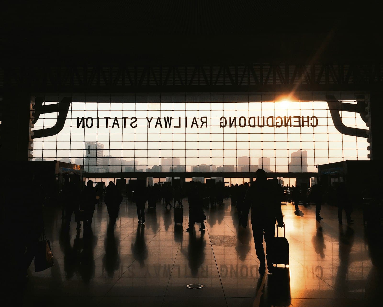 Reisende mit Koffern als Silhouetten in der Halle des Chengdu East Railway Station in Chengdu