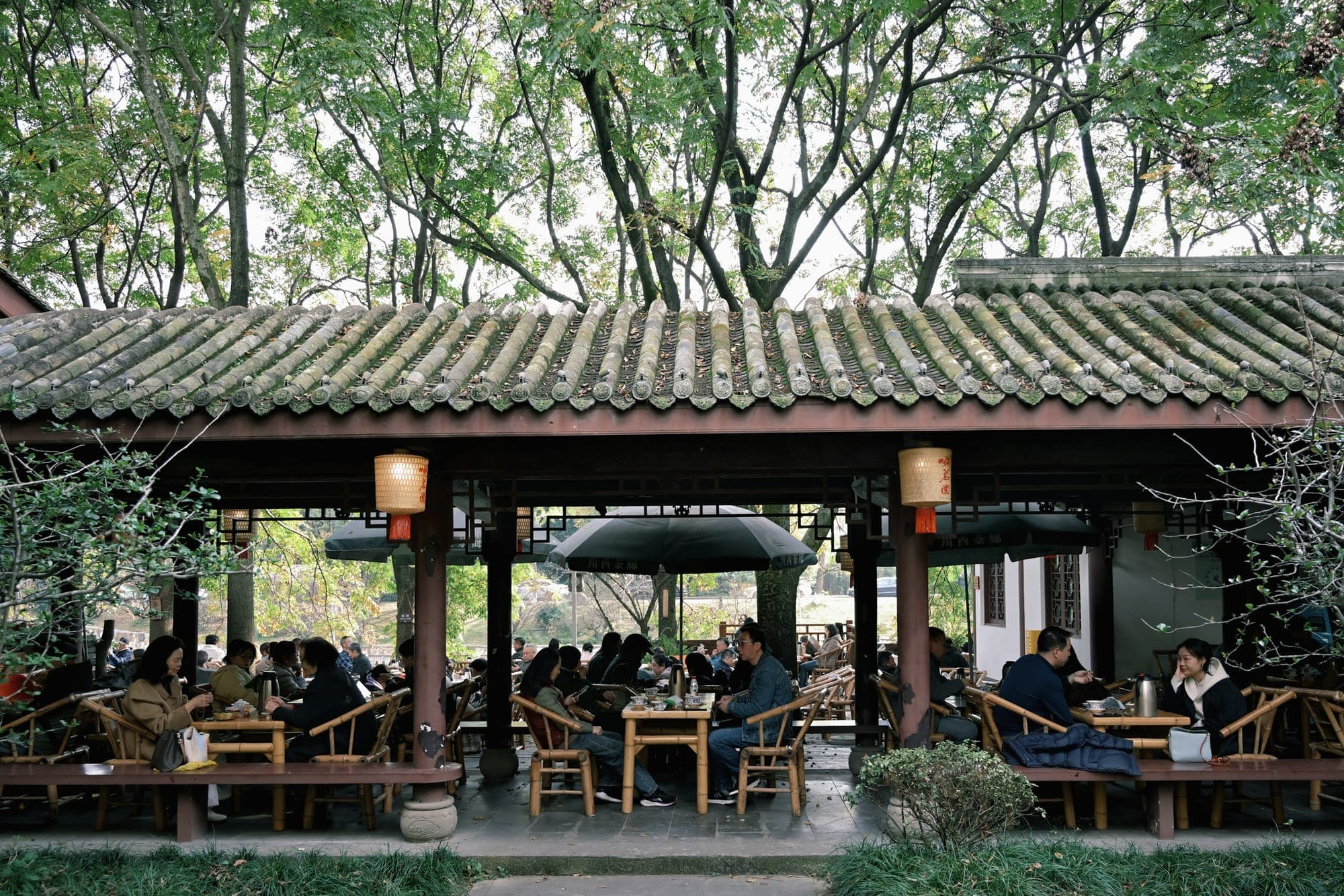 Menschen trinken Tee in einer Teestube unter freiem Himmel in Chengdu