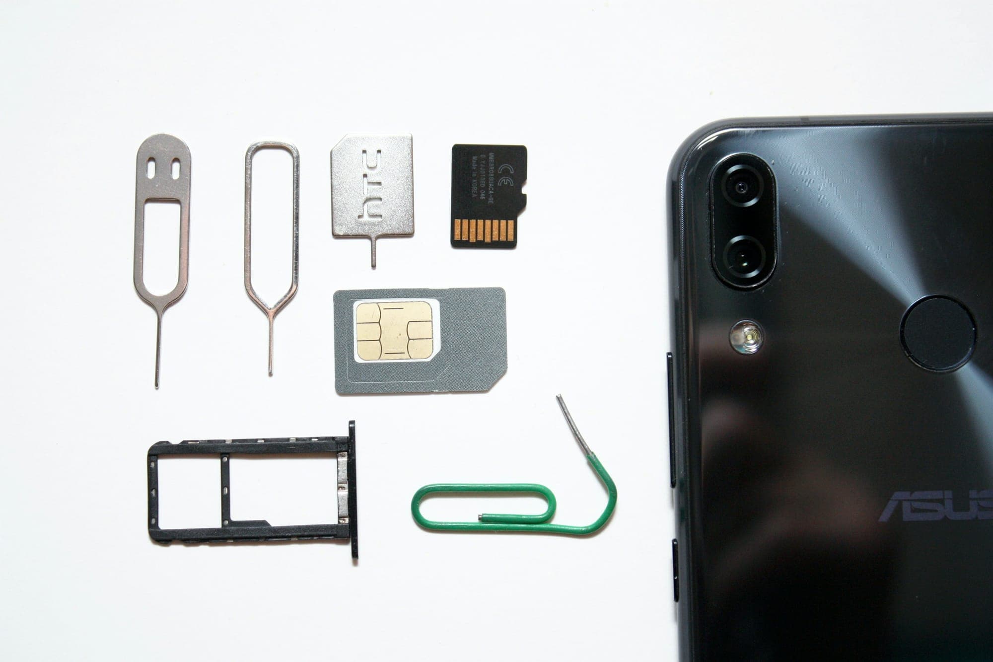Eine SIM-Karte, ein SIM-Fach und Auswurfstifte neben einem Smartphone