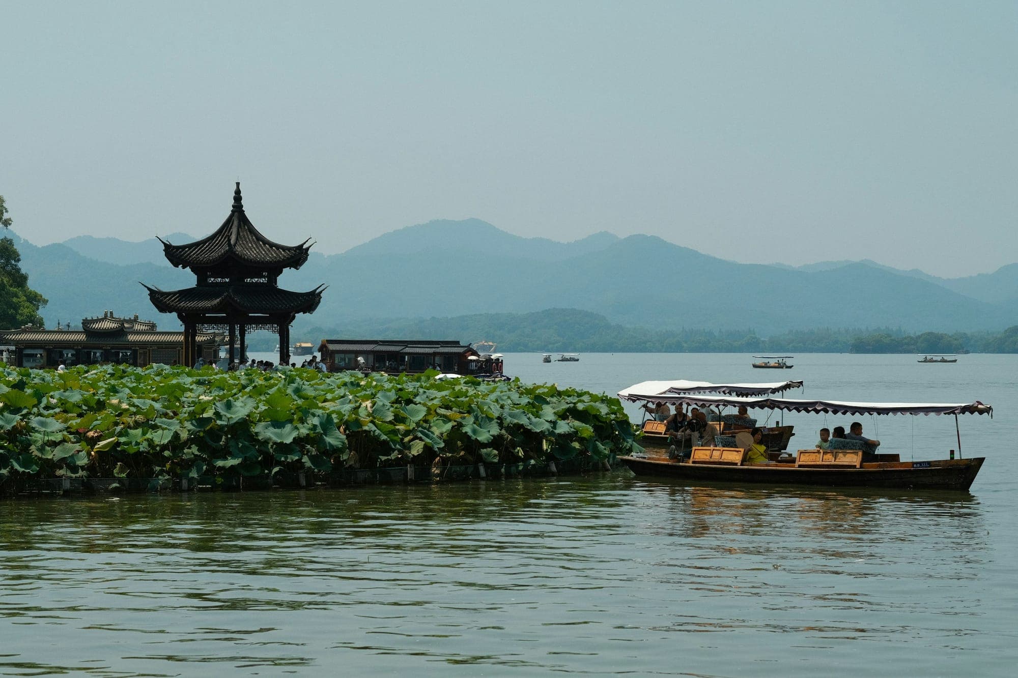 Un barco turístico y un pabellón ribereño en el Lago del Oeste, Hangzhou