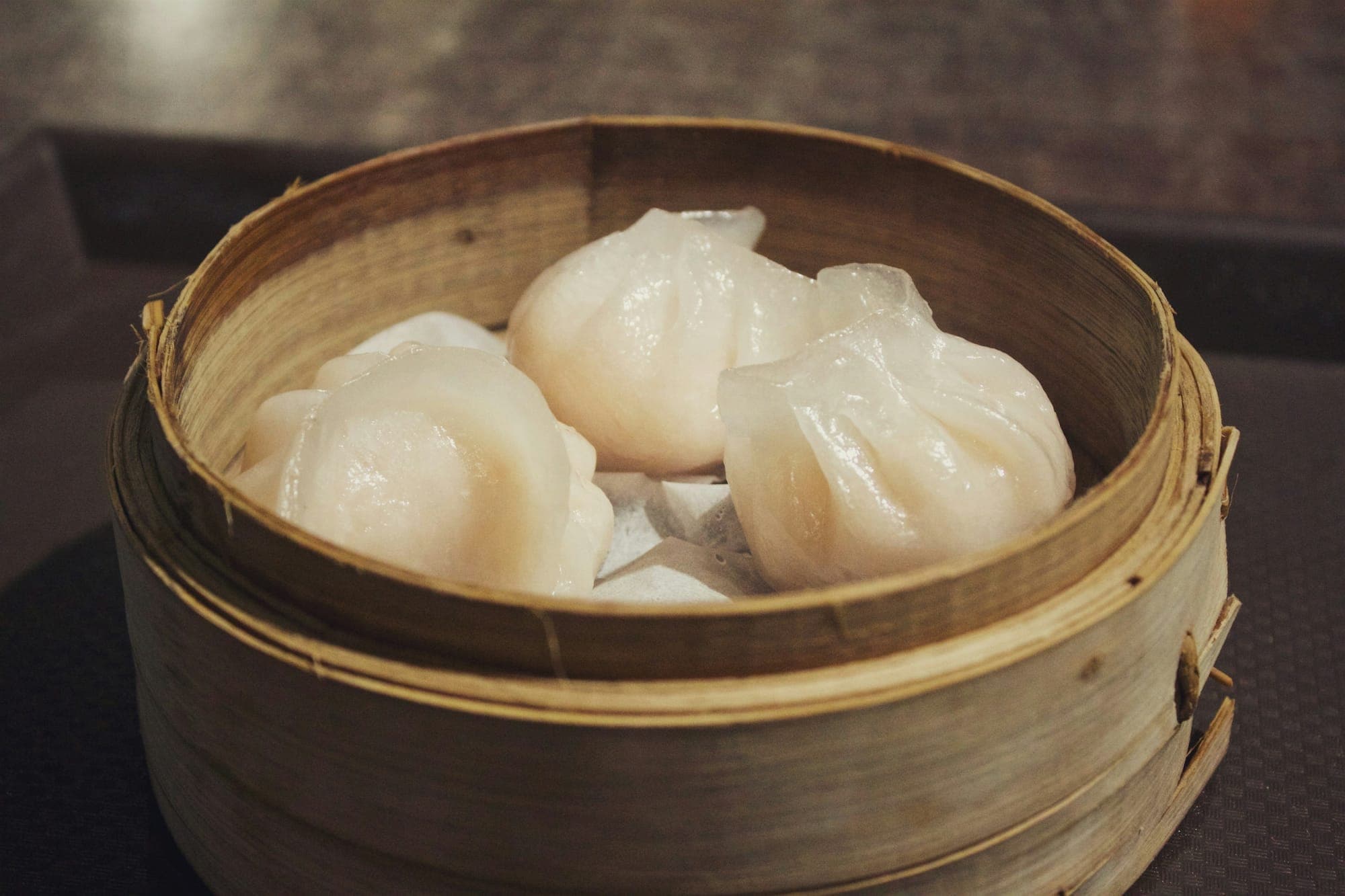 Raviolis aux crevettes translucides (har gow) dans un panier en bambou
