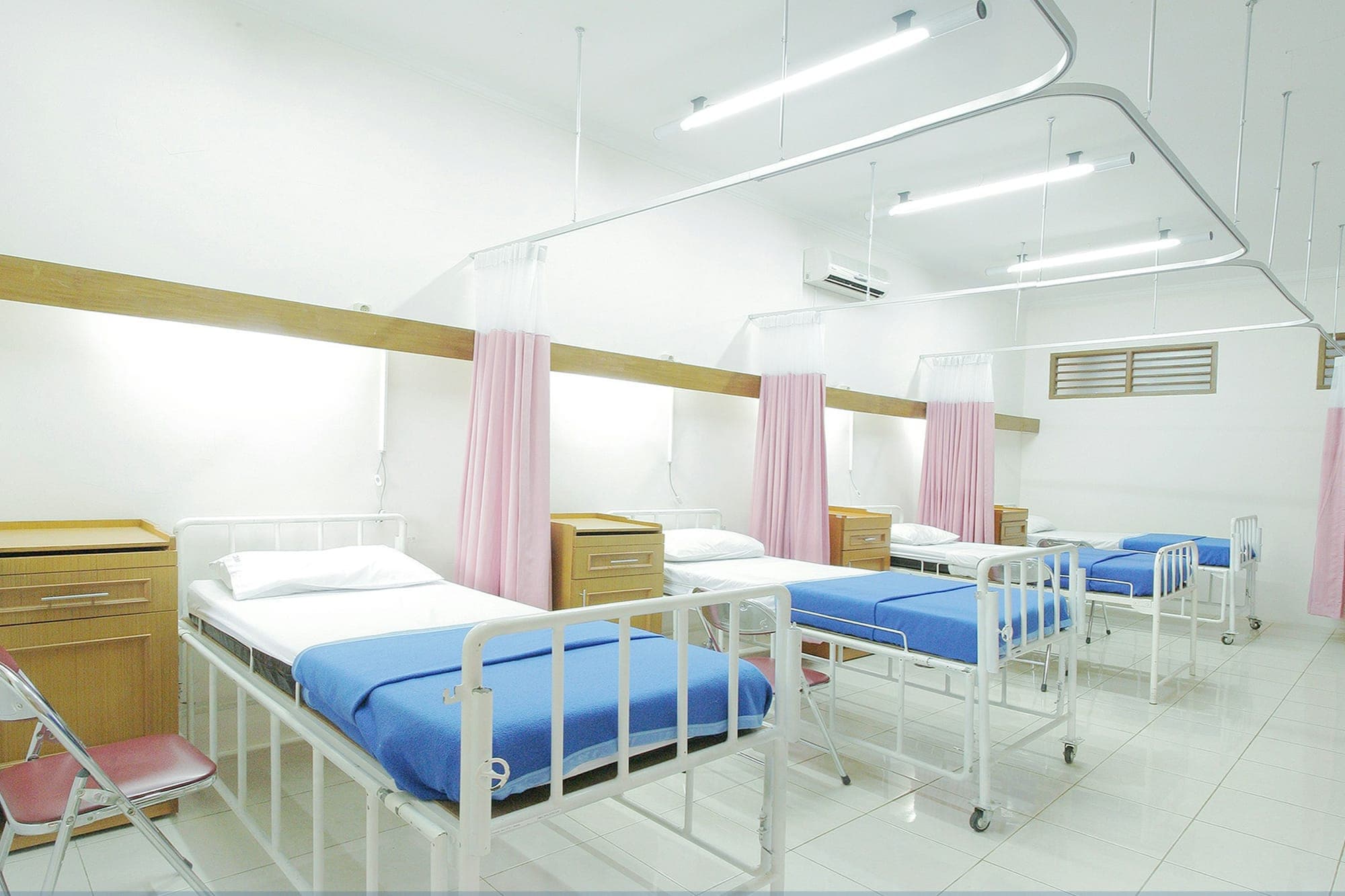 Reparto ospedaliero ordinato con letti e tende divisorie per la privacy
