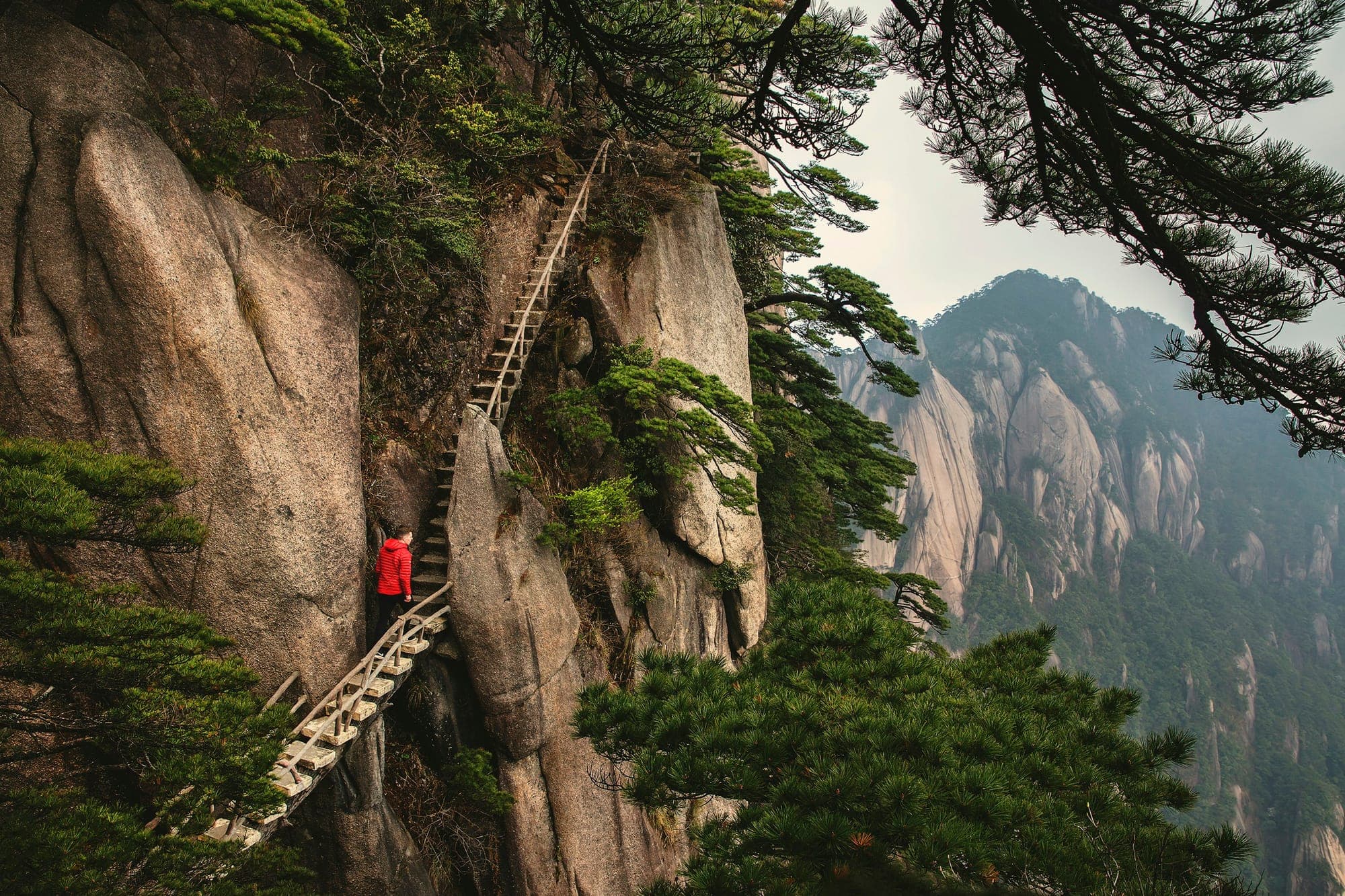 Un randonneur sur un escalier abrupt à flanc de falaise à Huangshan