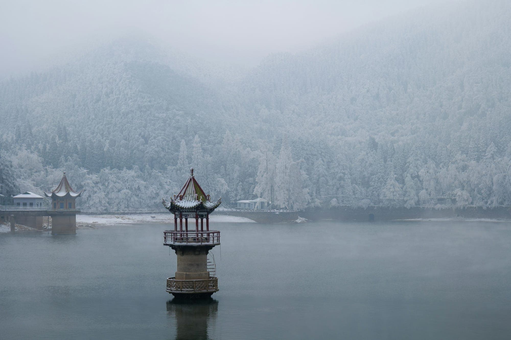 Un pabellón en un lago con niebla bajo un bosque escarchado en Lushan, Jiangxi