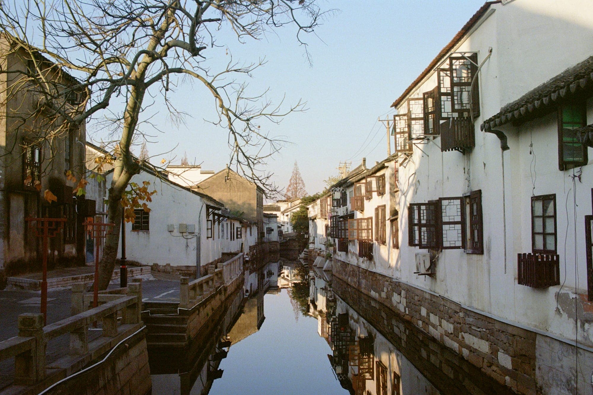 Weiß getünchte Häuser spiegeln sich in einem alten Kanal in Suzhou