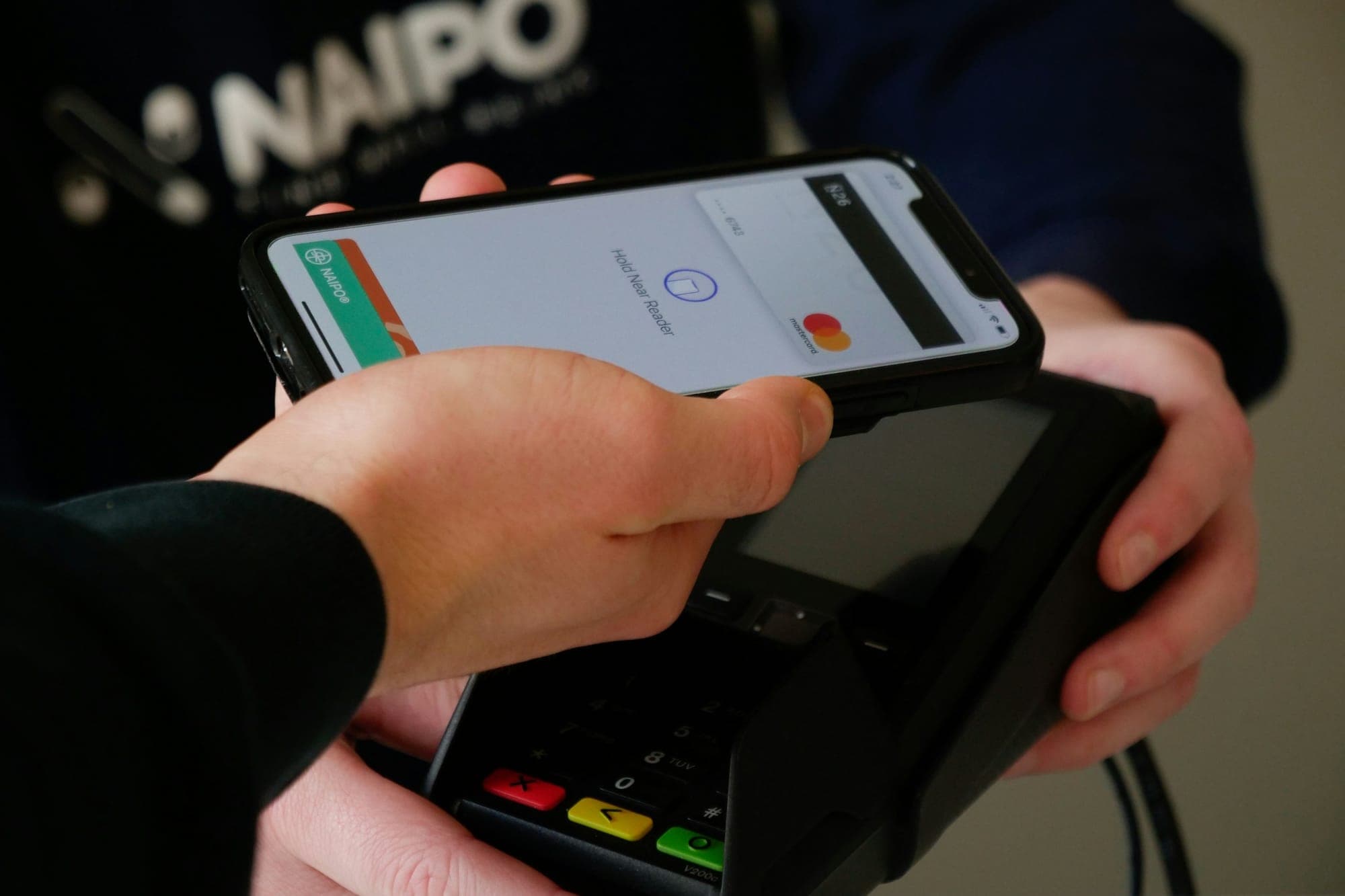 Un téléphone tenu au-dessus d'un terminal de carte pour payer