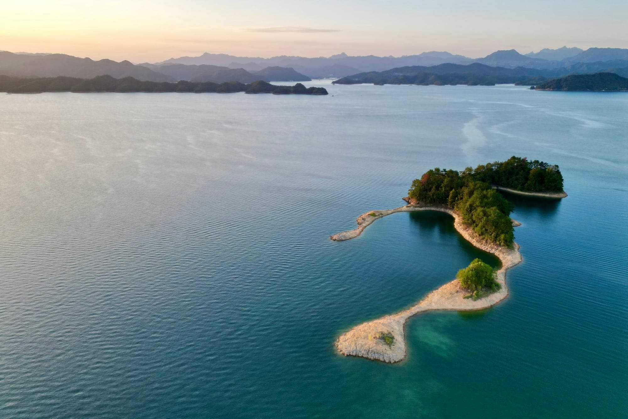 Una isla arbolada con una lengua de arena en el lago Qiandao, Zhejiang