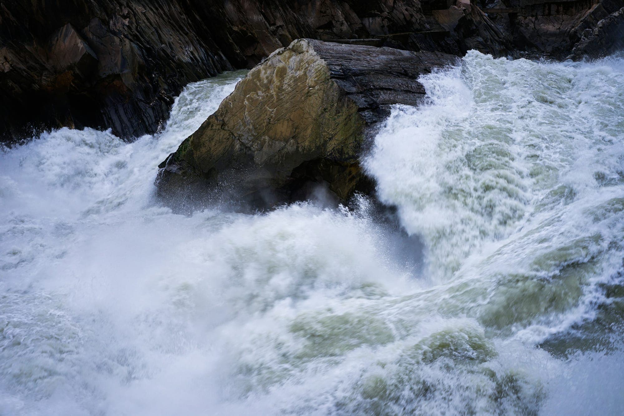 Ein Fluss verläuft unterhalb der steilen Bergwände der Tiger Leaping Gorge in Yunnan