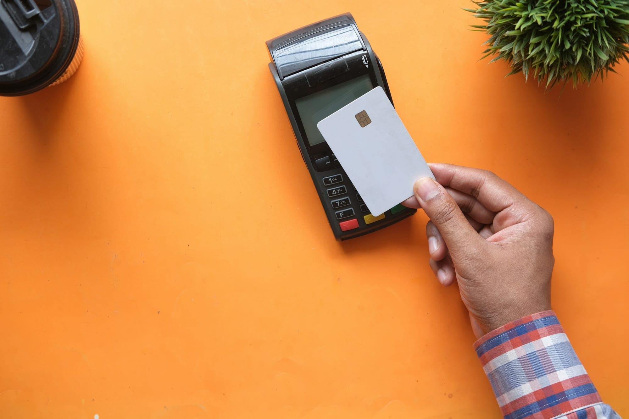 Una mano tiene una carta bancaria vicino a un terminale di pagamento
