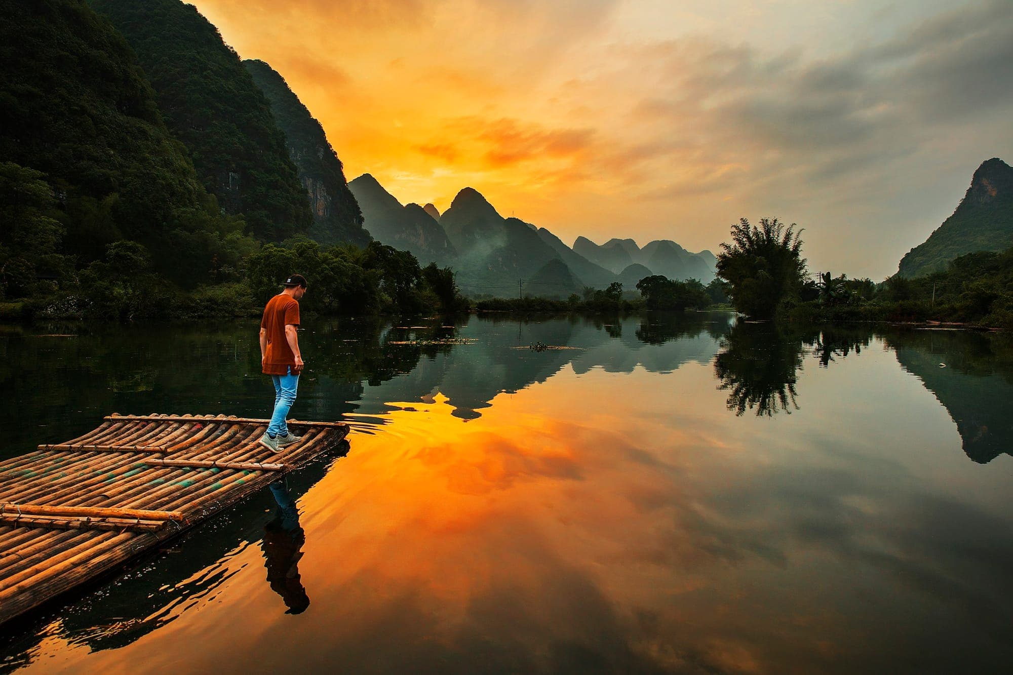 A man on a bamboo raft on the Yulong River near Yangshuo at sunset
