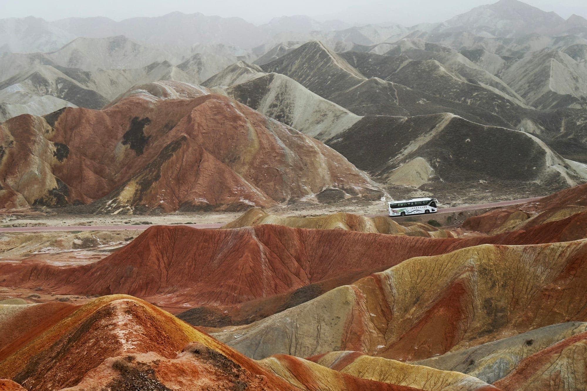 Collines de Danxia striées et autocar de tourisme à Zhangye, dans le Gansu