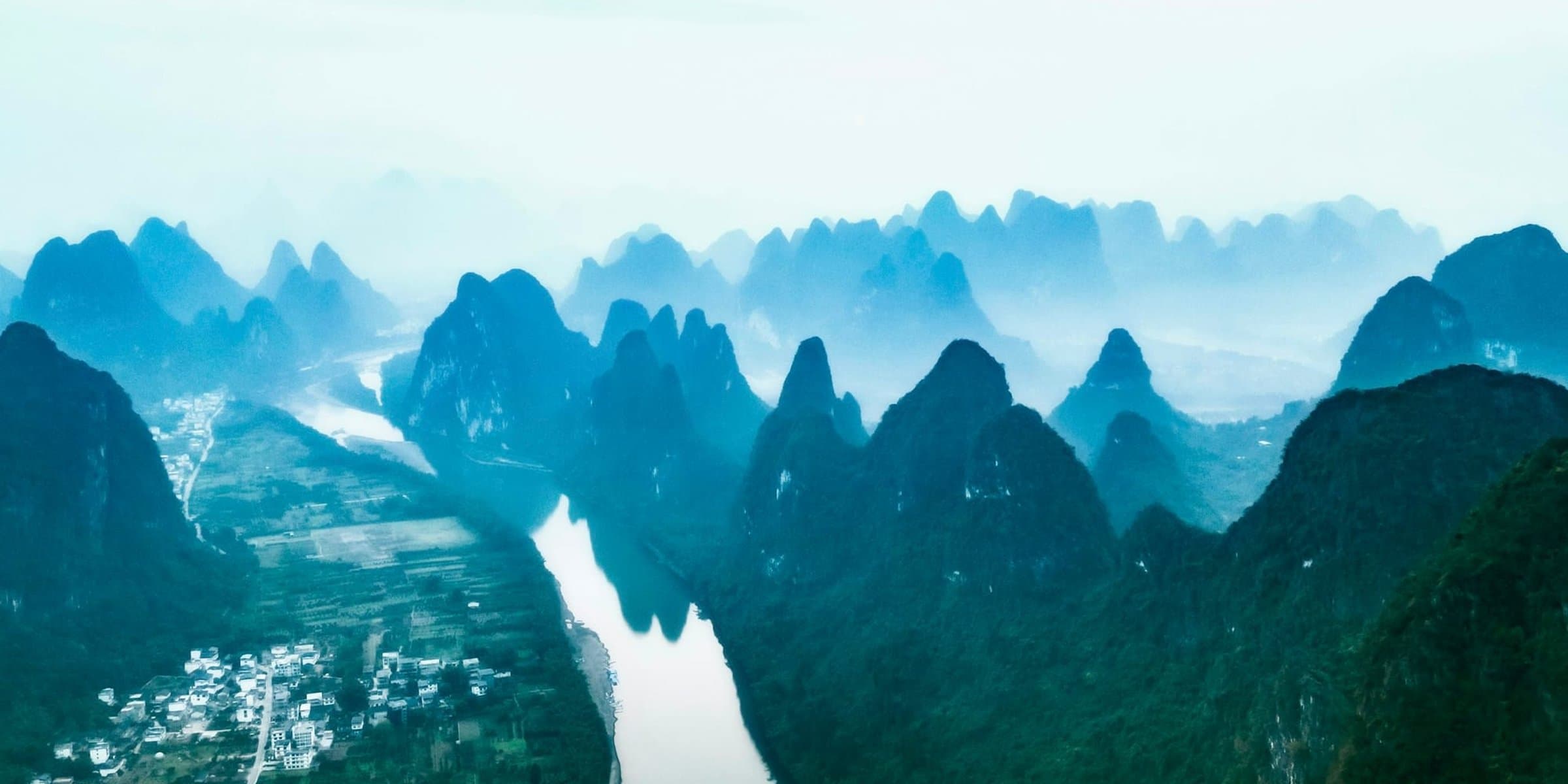 Der Li-Fluss zwischen den Karstgipfeln bei Guilin aus der Vogelperspektive an einem nebligen Tag