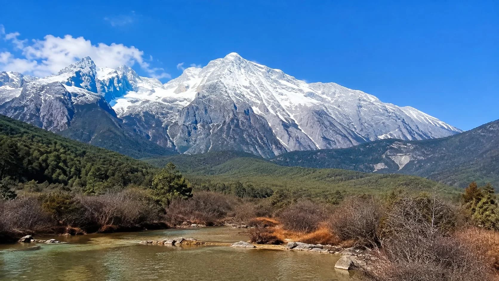 Jade Dragon Snow Mountain rising above the rooftops of Lijiang's UNESCO old town at dawn