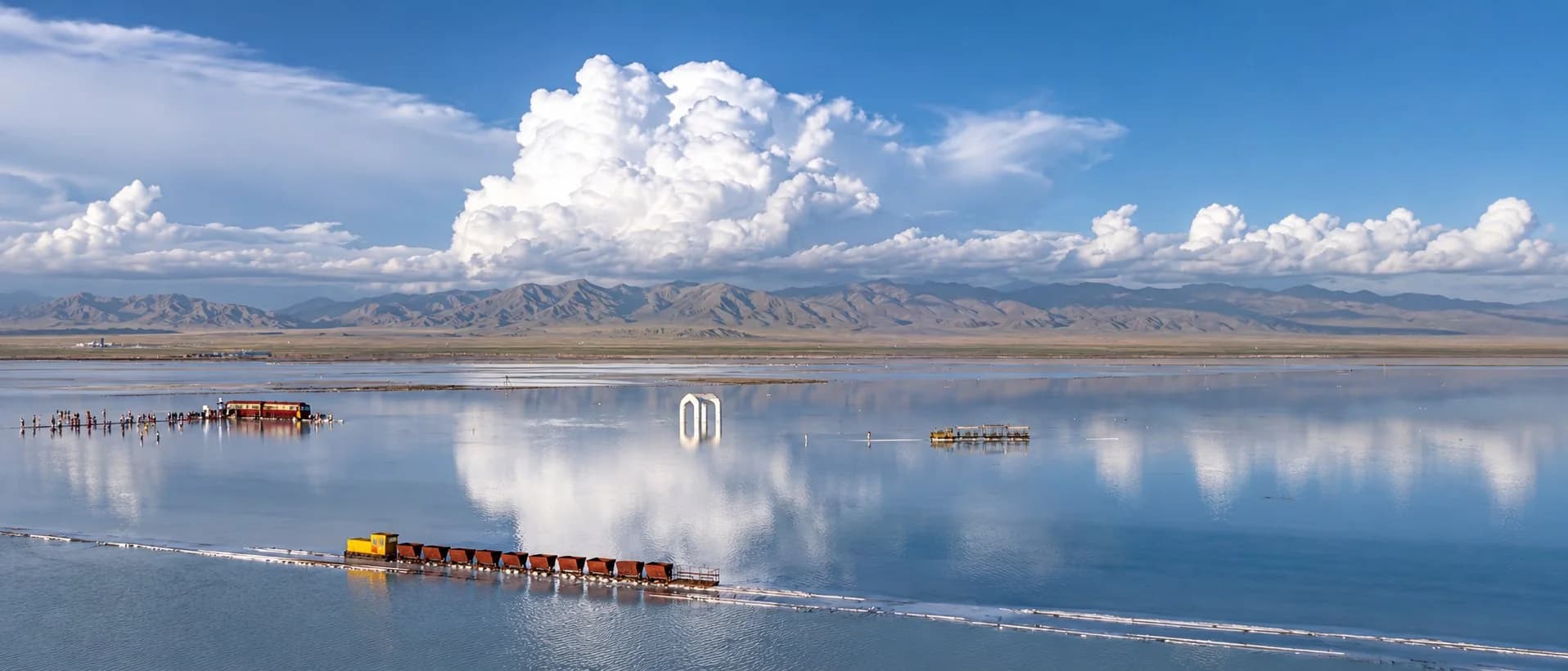 Lac salé aussi lisse qu'un miroir avec un train salinier à voie étroite, qui montre l'échelle des paysages de la Chine