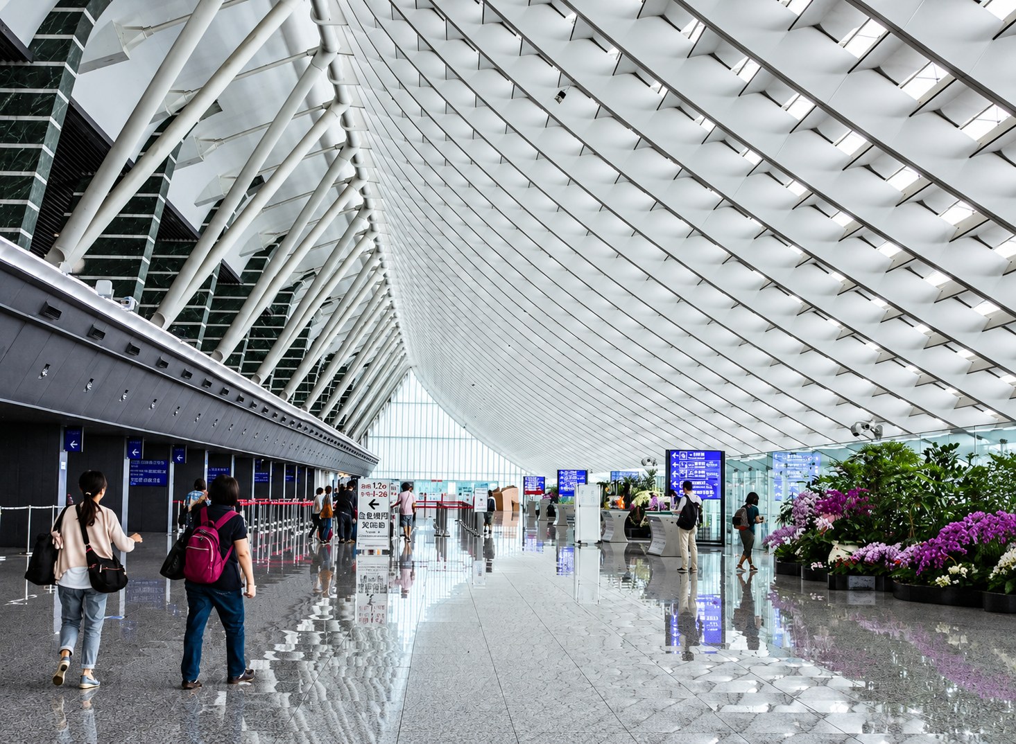 Interior view of an airport terminal with passengers and modern curved roof structure