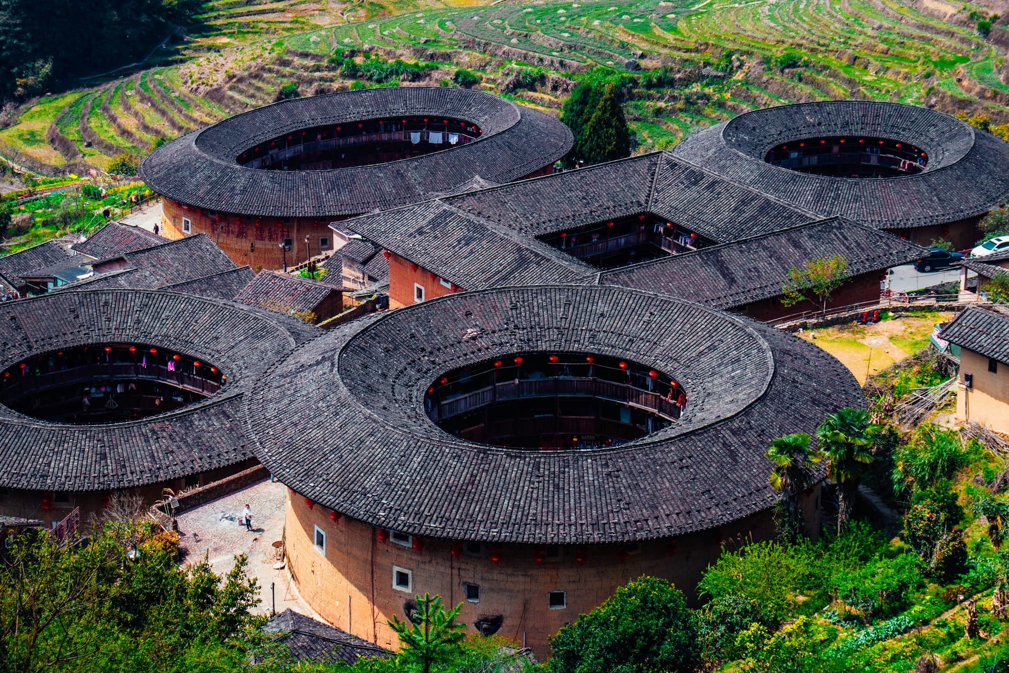 Vista aérea de edificios tulou redondos de tierra entre terrazas verdes