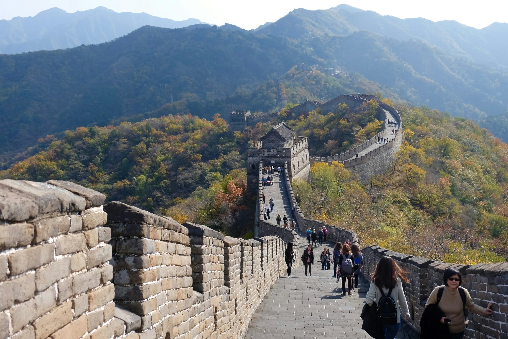 Reisende gehen an einem klaren Tag über einen restaurierten Abschnitt der Chinesischen Mauer
