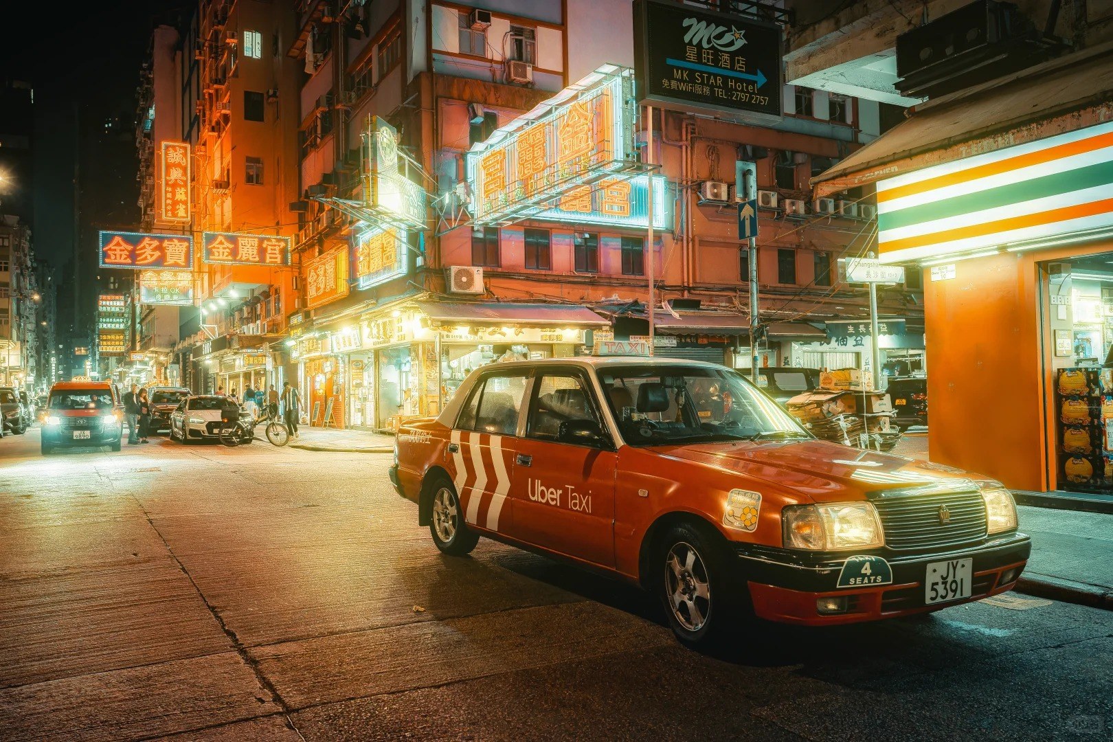 Classic red taxi amid neon street signs in Hong Kong at night.