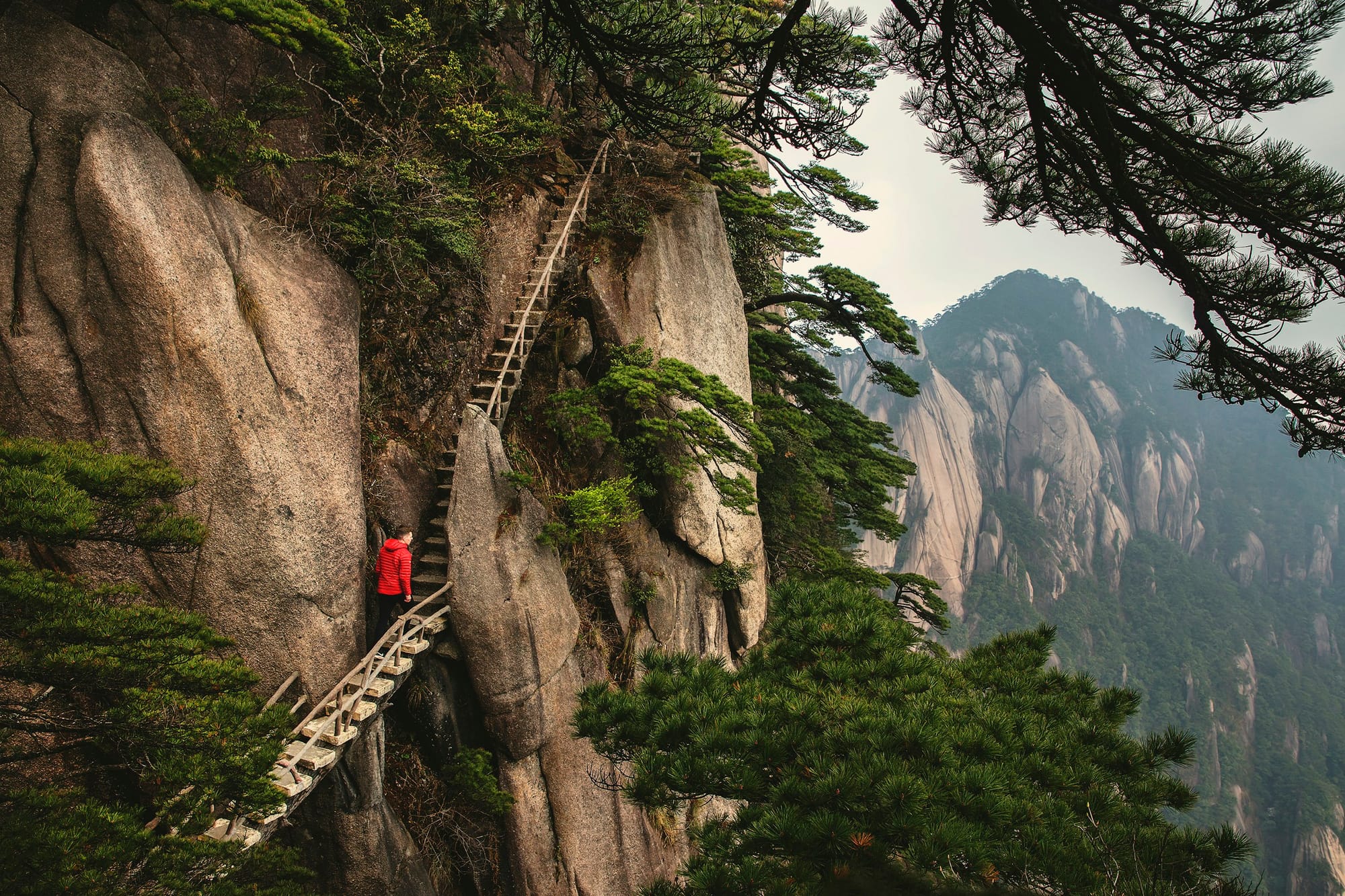Un senderista en una escalera empinada junto a un acantilado en Huangshan