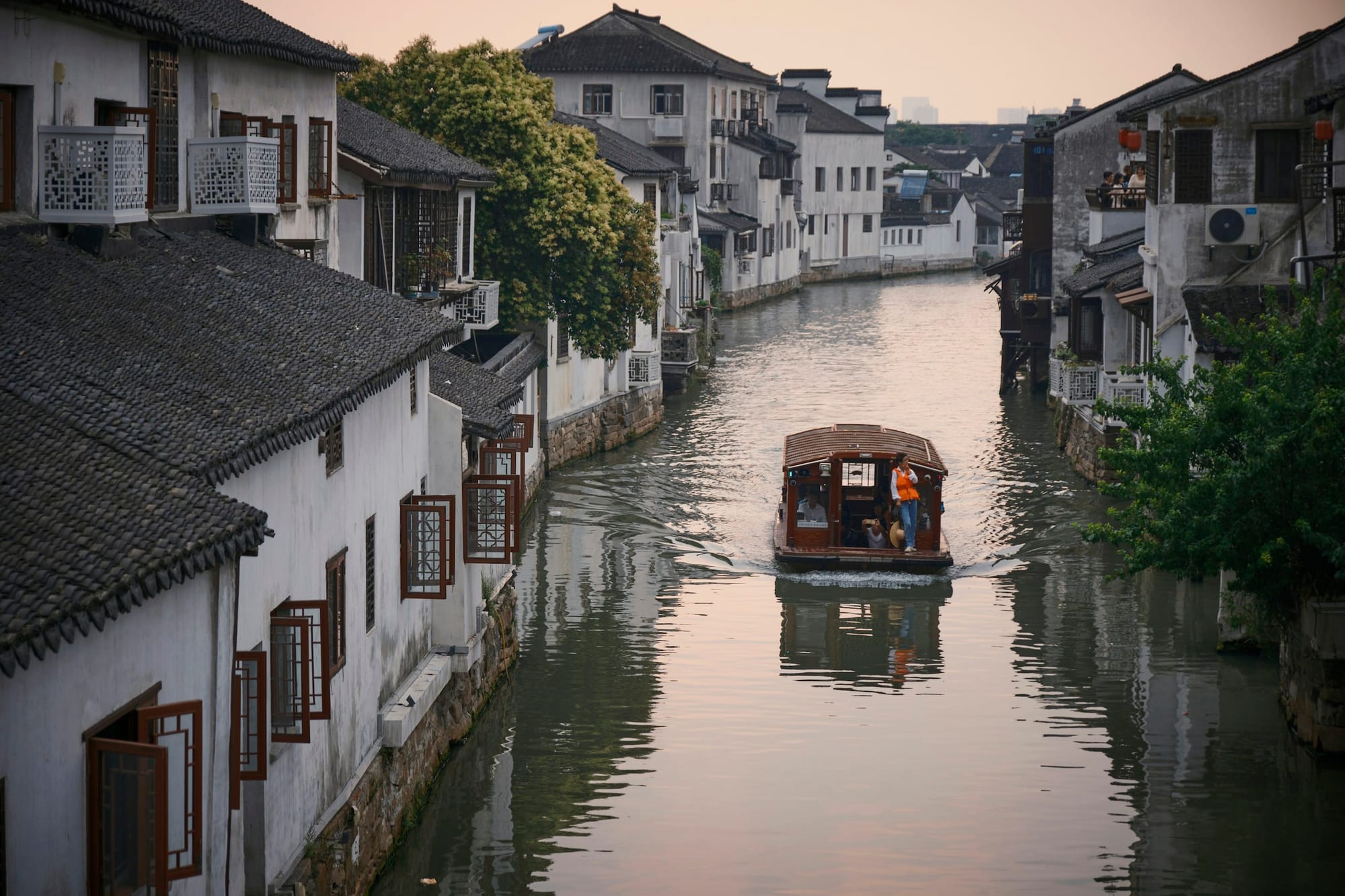 A boat on a canal between white-walled houses on Shantang Street, Suzhou
