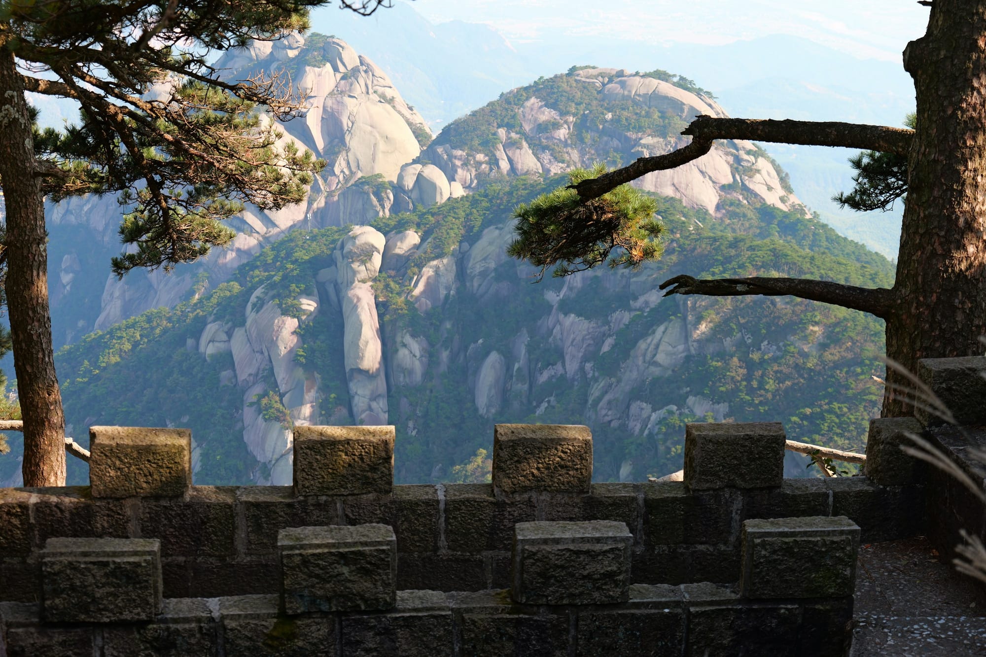 Cumbres de granito de la montaña Tianzhu vistas tras pinos y un parapeto de piedra, Anhui