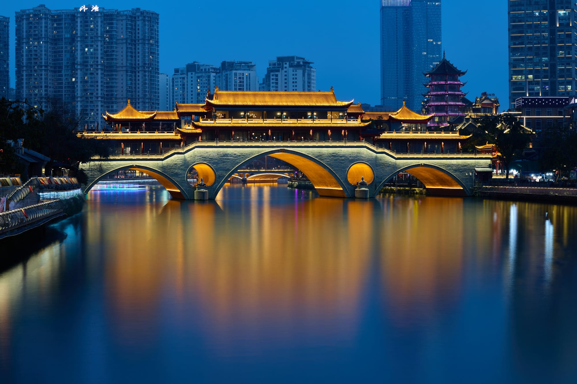 Die beleuchtete überdachte Anshun-Brücke bei Dämmerung über dem Jin-Fluss in Chengdu