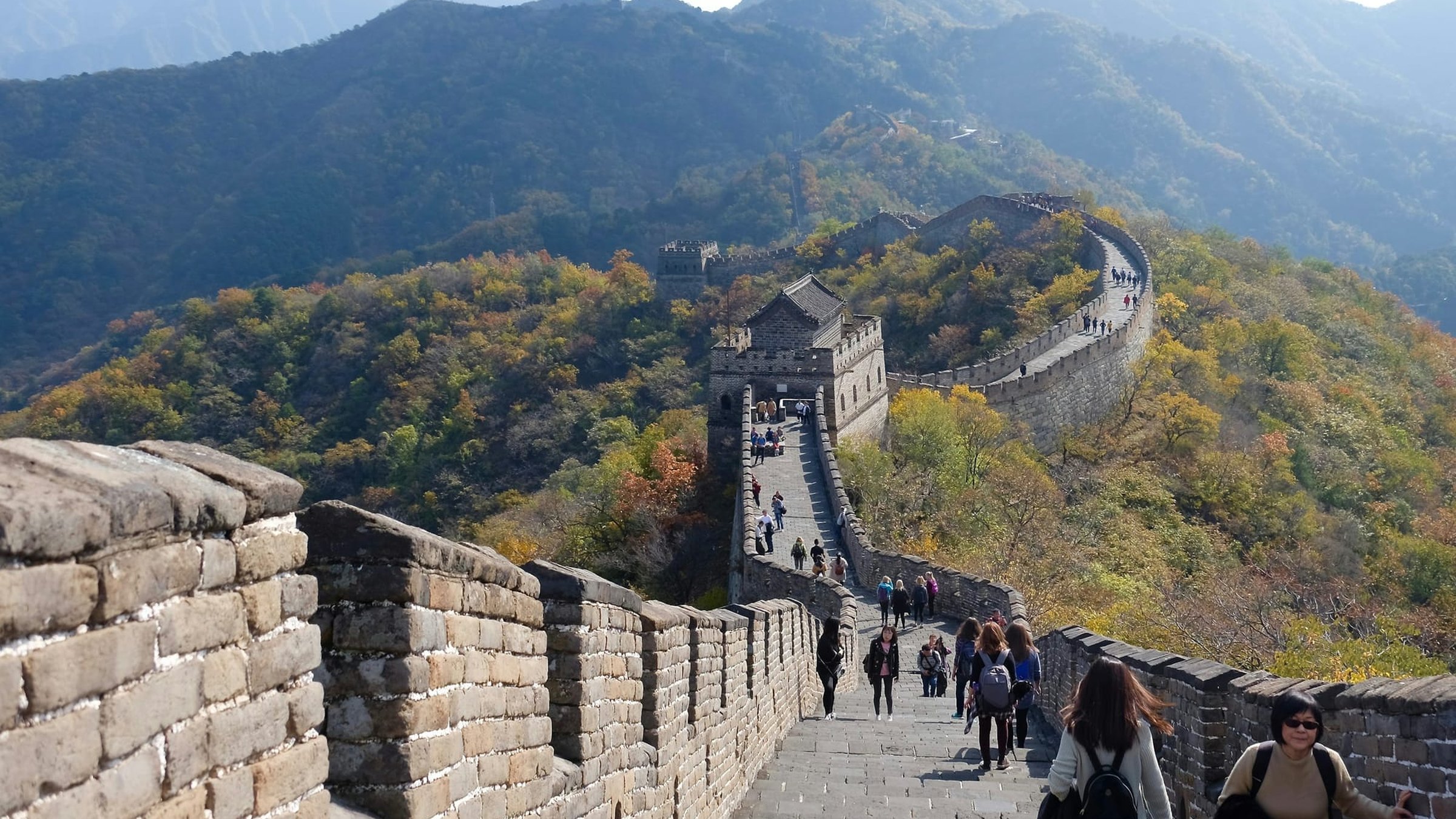 Visitors walking a restored section of the Great Wall of China on a clear day