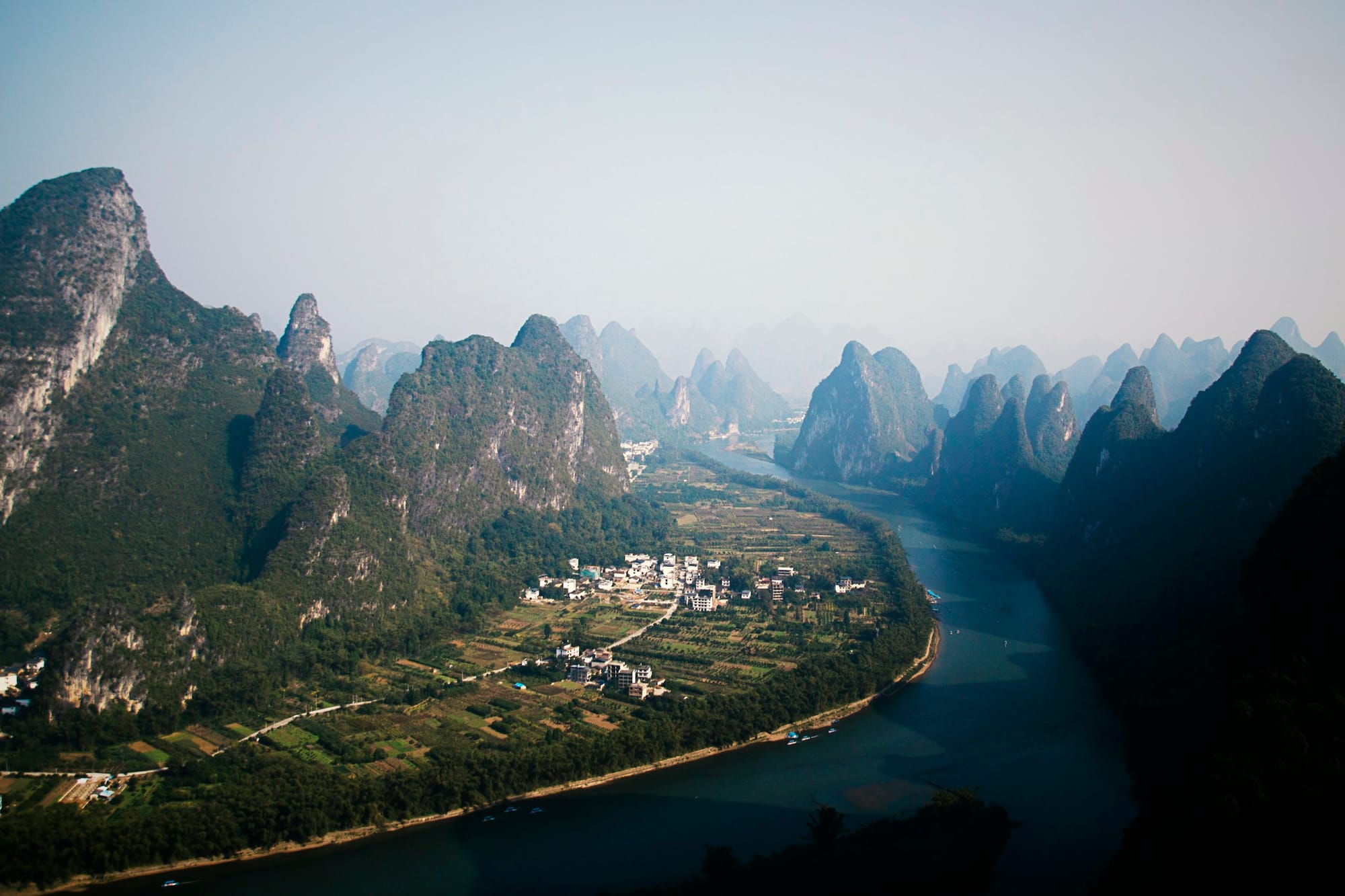 A bend of the Li River below karst peaks near Yangshuo, Guilin — a real landscape that informed Liyue's Dihua Marsh design